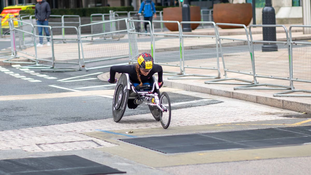 A dedicated athlete competes in a marathon using a racing wheelchair on city streets.